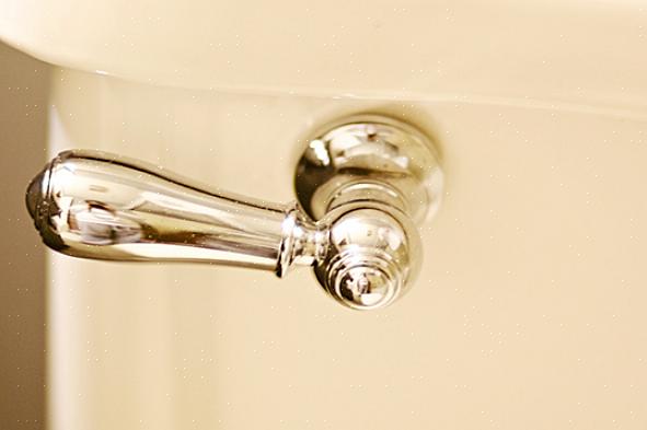 Blikkenslagerens kit fra bunden af toilettet ved hjælp af en spartel